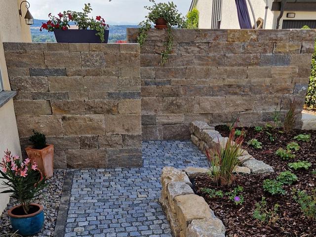 Natursteinmauer mit Pflanzbeeten