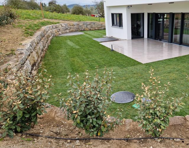 Garten mit Natursteinmauer, Rasen und Sträuchern