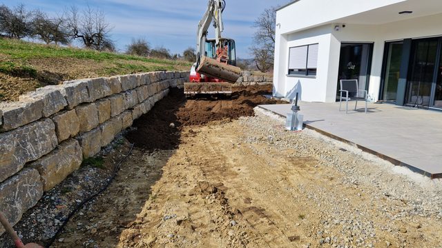 Erdarbeiten hinter der neuen Natursteinmauer
